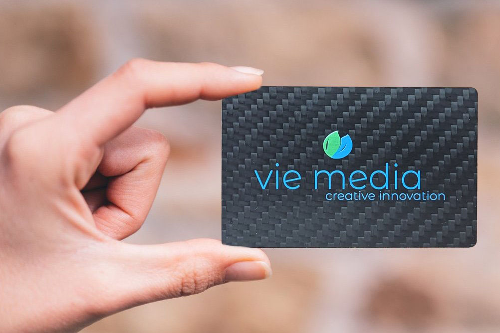 A person holding a Digital Business Card between their fingers. Vie Media